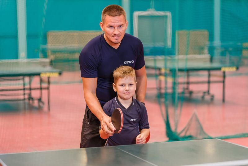 Tischtennistrainer mit seinem Schüler an einer Tischtennisplatte